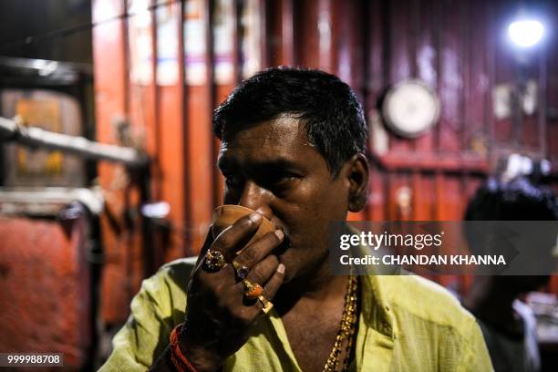 In this photograph taken on June 2, 2018 Bahadur Choudhary 48, drinks tea near his house at the Harishchandra Ghat in the old quarters of Varanasi. -...