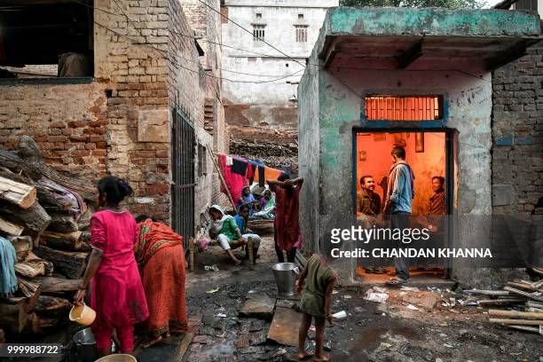In this photograph taken on June 2, 2018 members of a family who carry wood for cremations work near their house at the Harishchandra Ghat in the old...