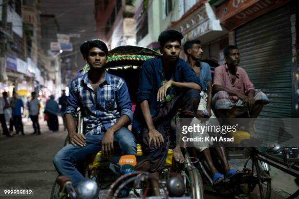 Bangladeshi Rickshaw pullers watch the Russia 2018 FIFA World Cup football final match between Croatia and France on projector screen at the street...
