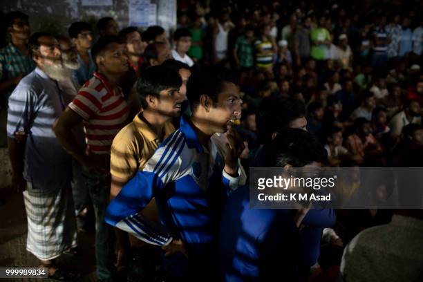 People watch the Russia 2018 FIFA World Cup football final match between Croatia and France on projector screen at the street in Dhaka.
