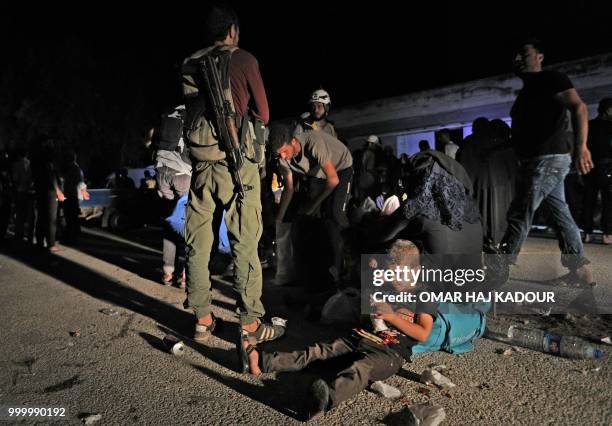 Displaced Syrians, who were travelling in a convoy carrying evactuated opposition fighters and their families from the southern province of Daraa,...