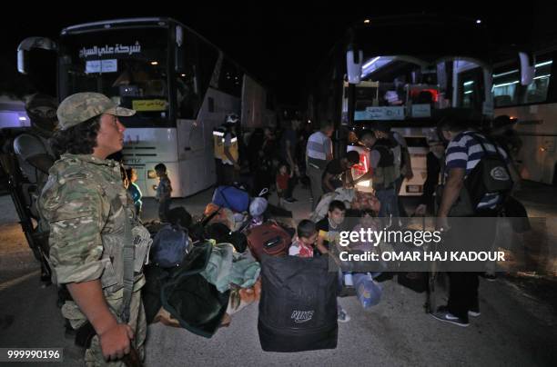 Displaced Syrians, who were travelling in a convoy carrying evactuated opposition fighters and their families from the southern province of Daraa,...