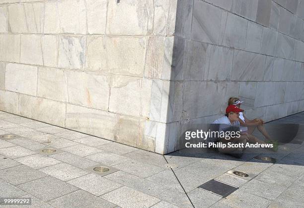 Walt and Cathy Prince, up from Mississippi, take shelter from the heat in the shadow of the Washington Monument. Temperatures in Washington D.C. Are...