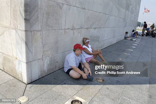 Walt and Cathy Prince, up from Mississippi, take shelter from the heat in the shadow of the Washington Monument. Temperatures in Washington D.C. Are...