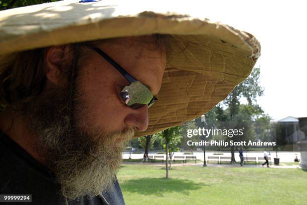 Rick Hohensee finds shade under a cardboard hat as he stands outside the White-house to protest both the war in Iraq and the recent dispute between...