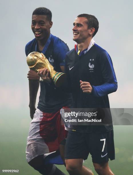 Antoine Griezmann of France and Presnel Kimpembe of France are seen with the trophy during the 2018 FIFA World Cup Russia Final between France and...