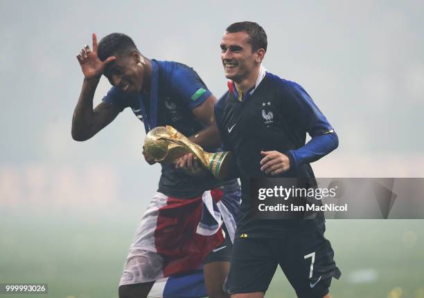 Antoine Griezmann of France and Presnel Kimpembe of France are seen with the trophy during the 2018 FIFA World Cup Russia Final between France and...