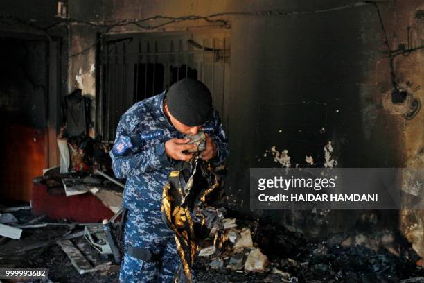 An Iraqi policeman kisses a recovered holy Koran from the premises of the Islamic Dawa Party that was torched during protests in the central shrine...