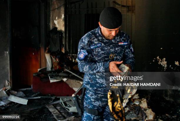 An Iraqi policeman holds a recovered holy Koran from the premises of the Islamic Dawa Party that was torched during protests in the central shrine...