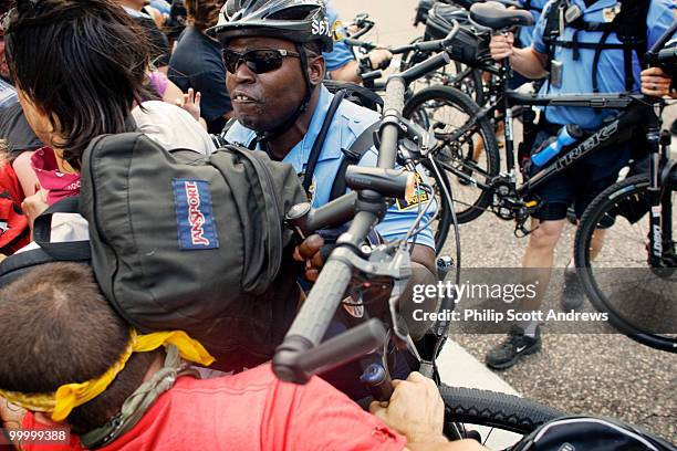 Police officer uses his bicycle to push back activists that were trying to prevent a delegate bus from reaching the convention center.