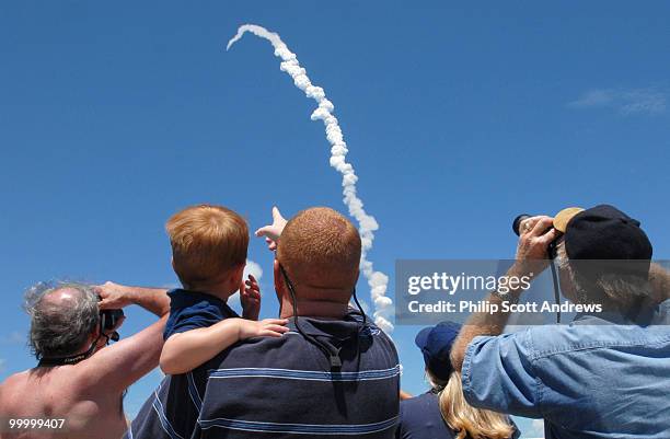 From across the Indian River Jack Willard watches his first launch from his father Chad's arms as the Space Shuttle Discovery lift off from Kennedy...