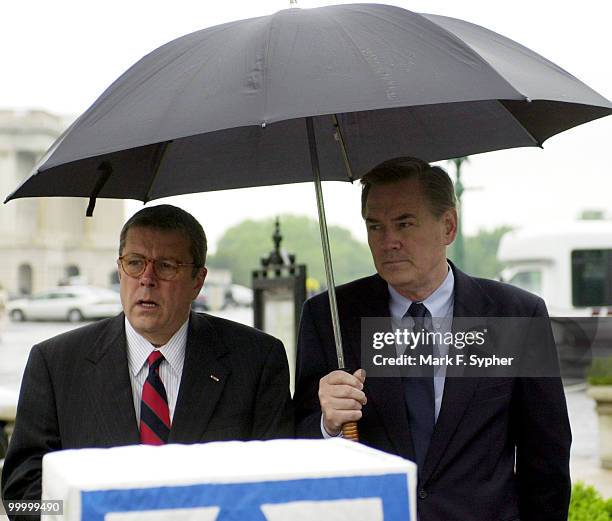 Rep. John S. Tanner and Rep. Dennis Moore find a common shelter during a rainy press conference on Thursday at the House Triangle which outlined "The...