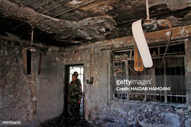 Iraqi policemen walk through the torched premises the Islamic Dawa Party that was burnt during protests in the central shrine city of Najaf on July...