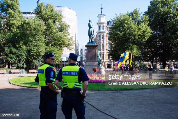 Police officers stand guard during a small protest of Ukrainian against Russia on early July 16 in the Esplanadi park in Helsinki, Finland, some...