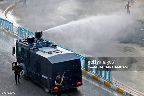 Demonstrators are sprayed by water cannon employed by the Iraqi security forces during protests in the central shrine city of Najaf on July 14, 2018....