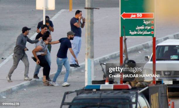 Members of the Iraqi security forces detain a protester in the central shrine city of Najaf on July 14, 2018. - Unrest in southern Iraq erupted on...