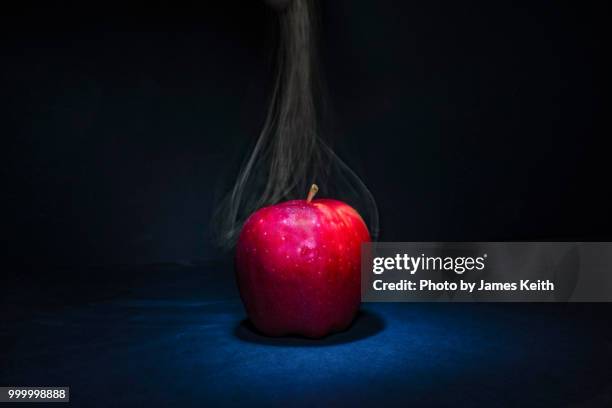 smoke appears to be emanating from a red apple in the spotlight. - banks post near record profits in second quarter of 2014 stockfoto's en -beelden