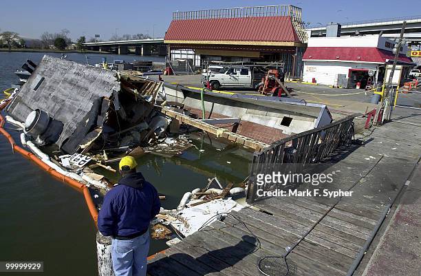 Construction worker, who wished to go unnamed, surveys the scene where the Custis Brown Fish Store used to float, until a fire about a week ago, at...
