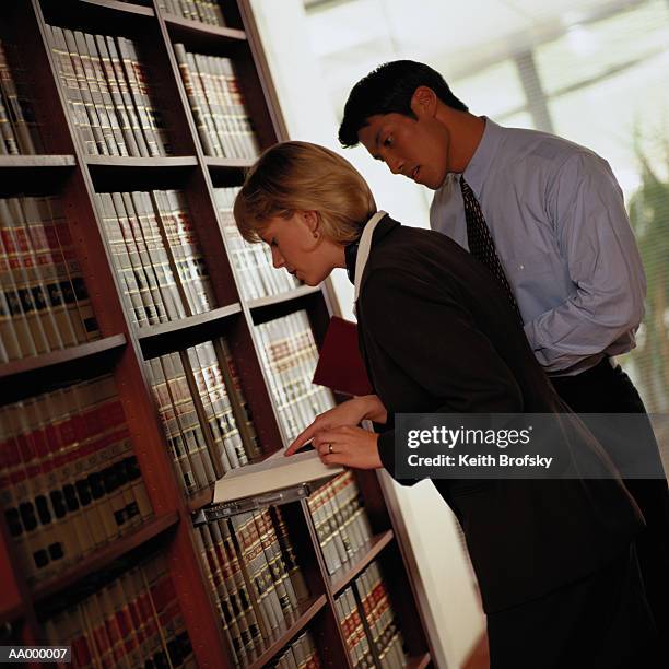 lawyers researching information in a law library - diagonal bookshelf photos et images de collection