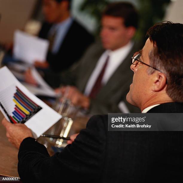 businessman holding a bar graph in a meeting - bar graph stockfoto's en -beelden