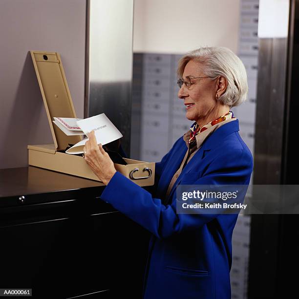 woman looking at contents of a safe deposit box - safe deposit box stock pictures, royalty-free photos & images