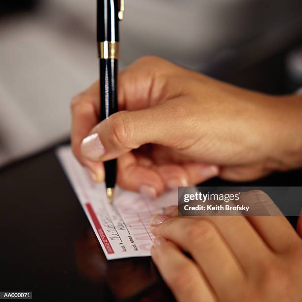 woman filling out a deposit slip - bank deposit slip fotografías e imágenes de stock