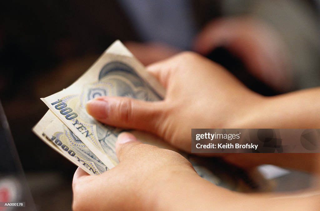 Teller Counting Money at a Currency Exchange