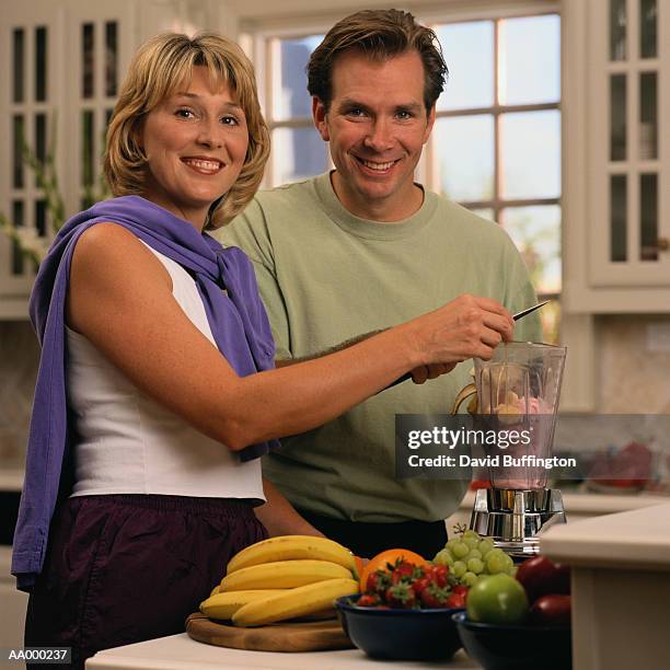 couple making a fruit drink in a blender - blender stock-fotos und bilder