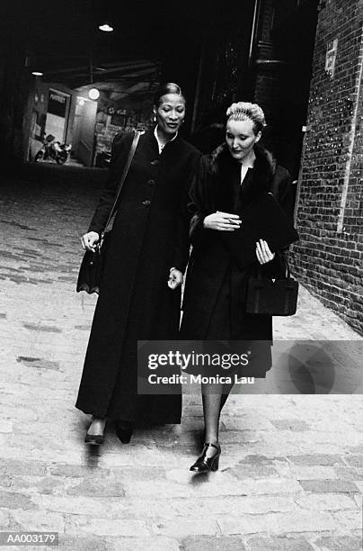 woman in overcoats walking in an alley together - monica askew stock pictures, royalty-free photos & images