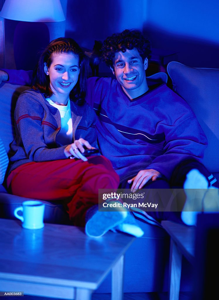 Smiling Couple on a Couch Watching Television