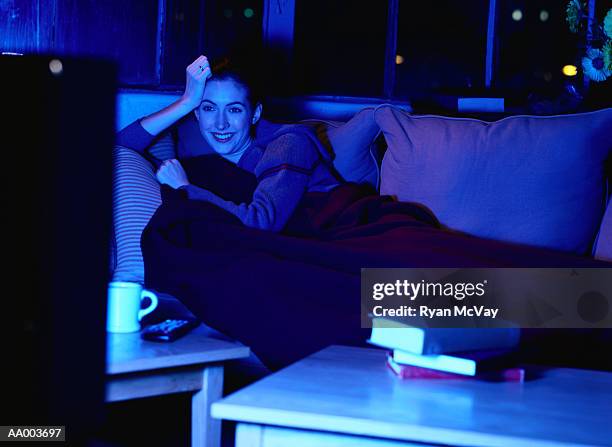 smiling woman watching television - avond thuis stockfoto's en -beelden