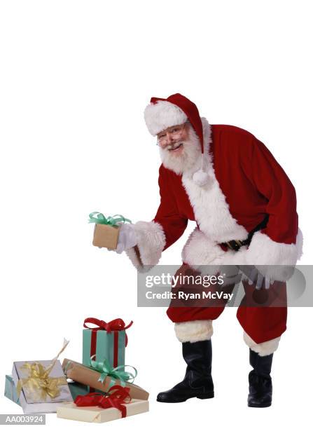 santa claus adding to a stack of christmas gifts - santa leaning stock pictures, royalty-free photos & images