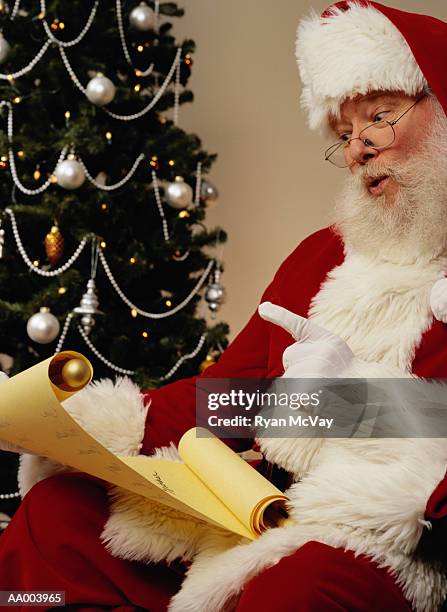 santa claus reading a list of bad boys and girls - bad santa stock pictures, royalty-free photos & images