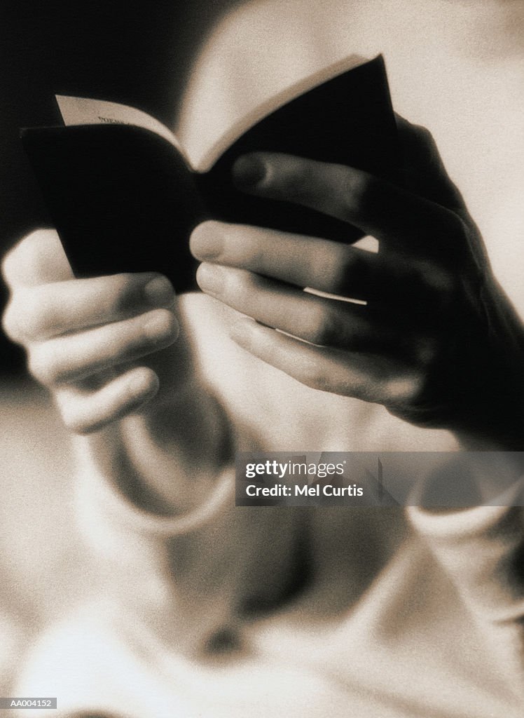 Close-Up of a Person Reading a Small Book