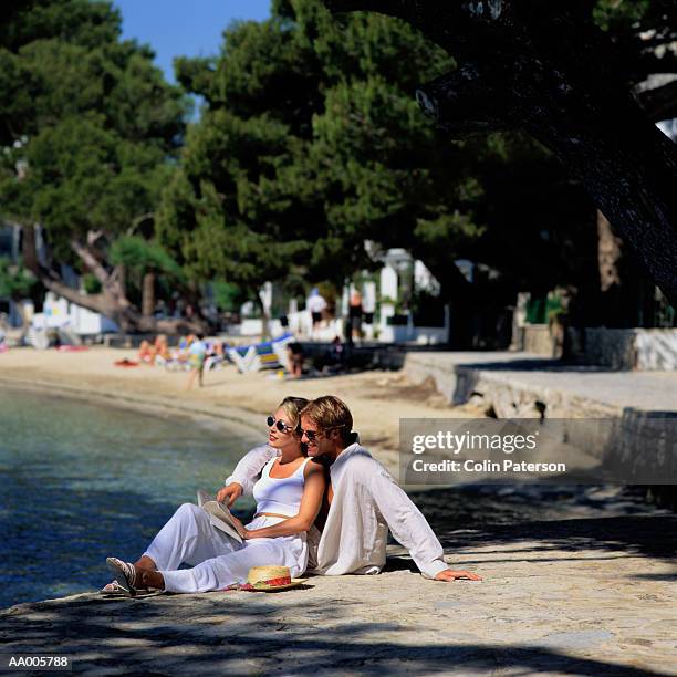 couple sitting beside the bay in puerto pollensa - puerto stock-fotos und bilder