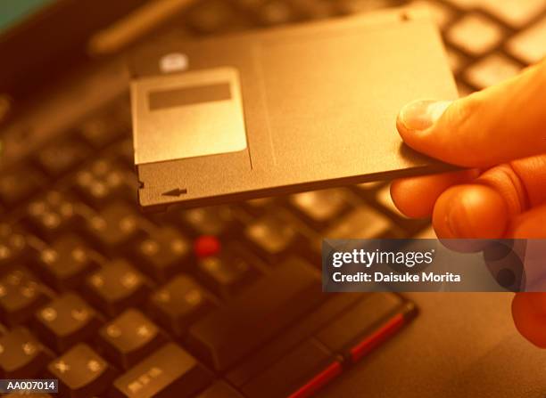 floppy disk over a computer keyboard - floppy-disk-hand stock pictures, royalty-free photos & images