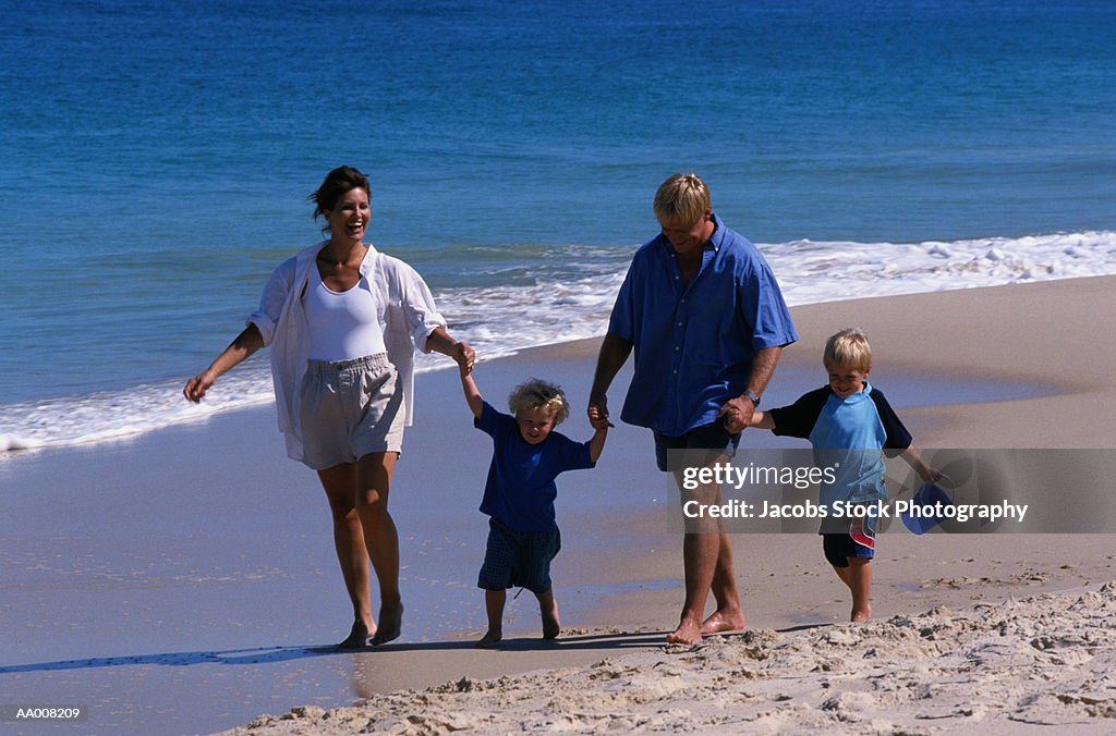 Family Holding Hands and Walking on the Beach
