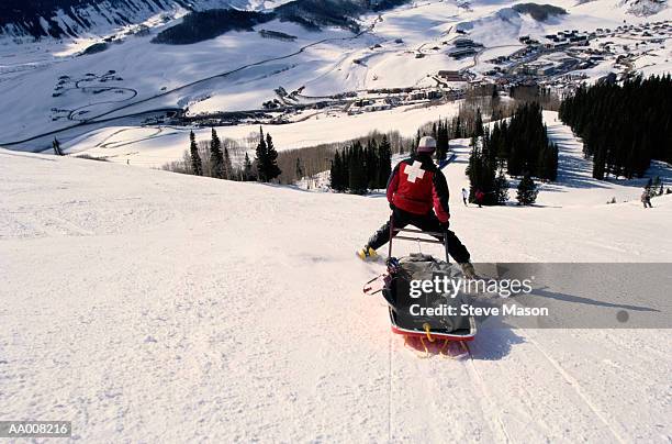 ski patrol member guiding a stretcher - ski patrol stock-fotos und bilder