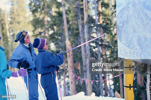 woman pointing at a sign with her ski pole - ski pole stock-fotos und bilder