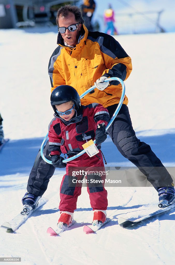 Man Teaching His Daughter to Ski Using a Hoop