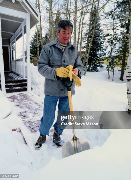 man shoveling the front walkway - older man snow shovel stock pictures, royalty-free photos & images