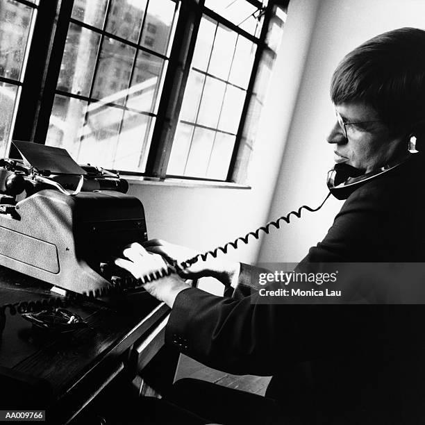 businessman typing and talking at desk - monica askew stock pictures, royalty-free photos & images