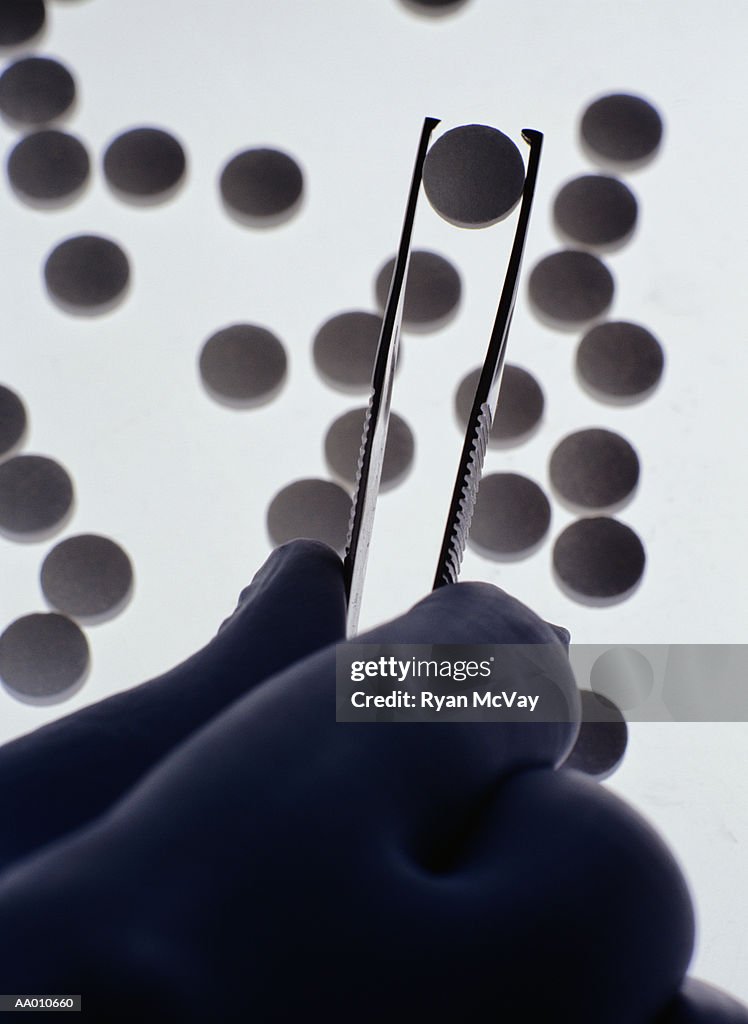 Person Handling Pills with Forceps