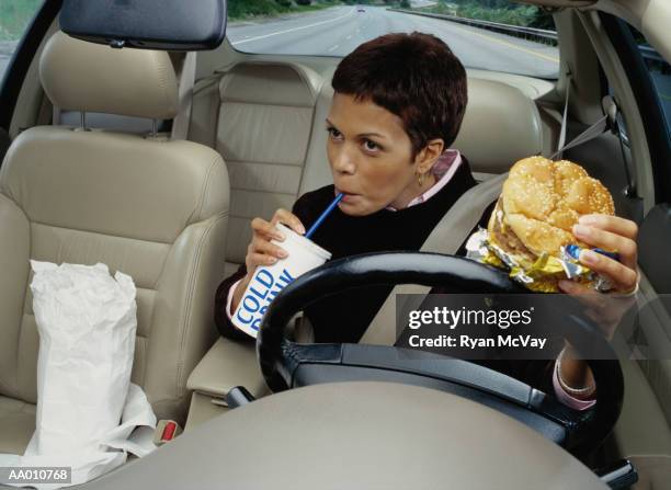 woman eating fast food while driving - sesame seed bun stock pictures, royalty-free photos & images