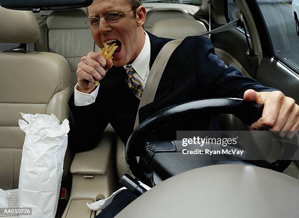 businessman eating french fries while driving - suprasensorial - fotografias e filmes do acervo