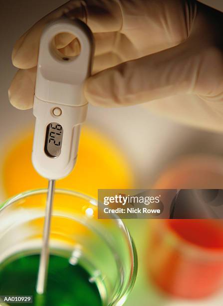 scientist holding digital thermometer in a beaker - thermomètre à affichage digital photos et images de collection