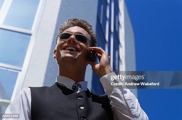 smiling businessman on a cellular phone - young urban professional person stock-fotos und bilder