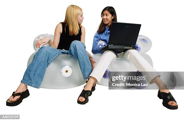 girls sitting on inflatable chairs with a laptop - bubble chair stock-fotos und bilder