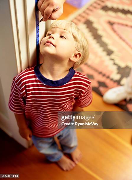 mother measuring height of her son (3-5) in door frame - kids growth chart stock pictures, royalty-free photos & images