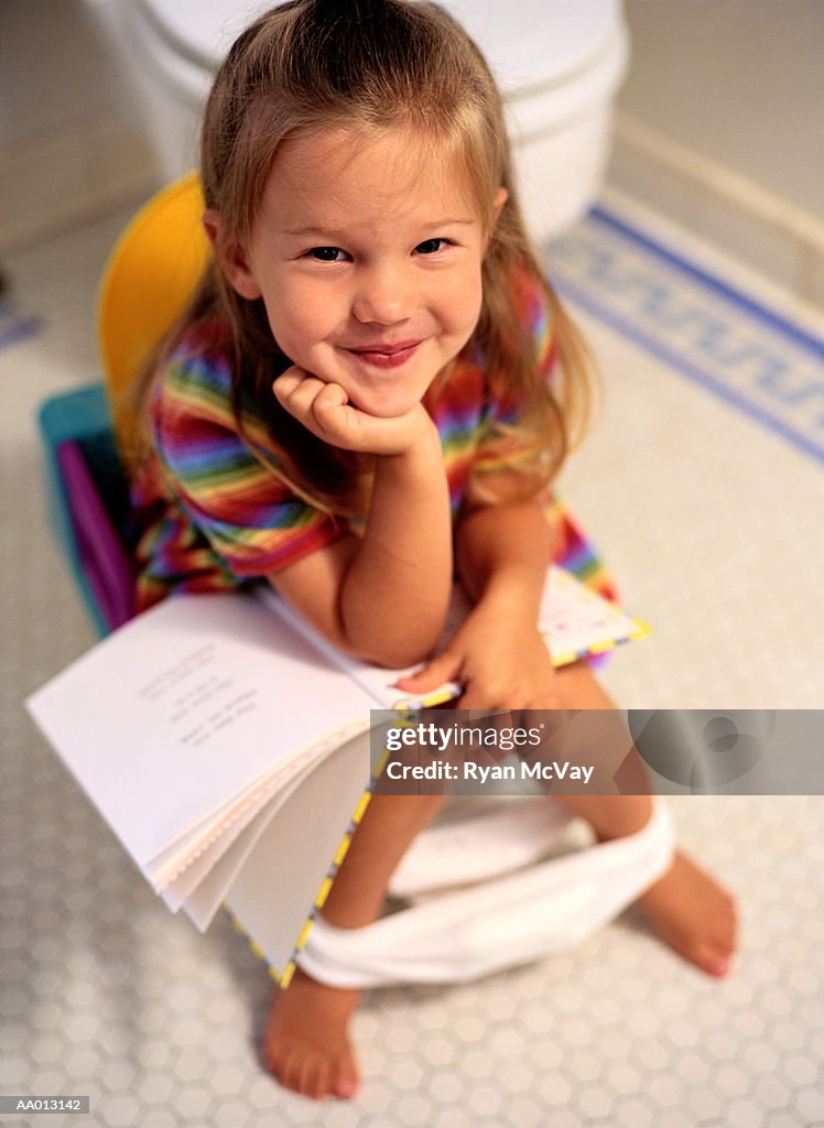 Girl Reading a Book on a Potty Chair